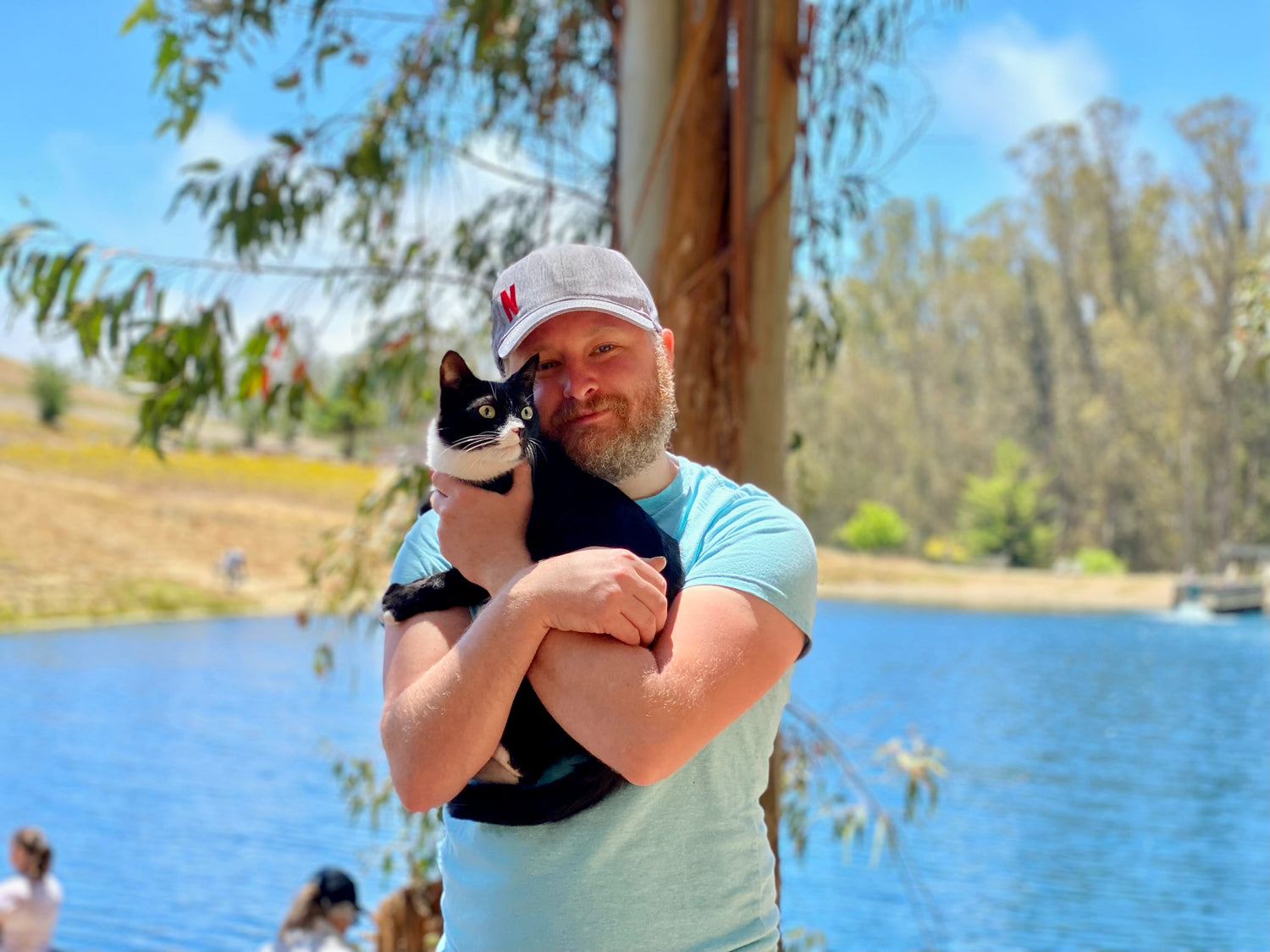 Founder Ben Brumbaugh holds his cat by a lake. 